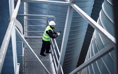 factory-silos-worker-standing-metal-platform-industrial-storage-tanks-looking-tablet-about-food-production_342744-440